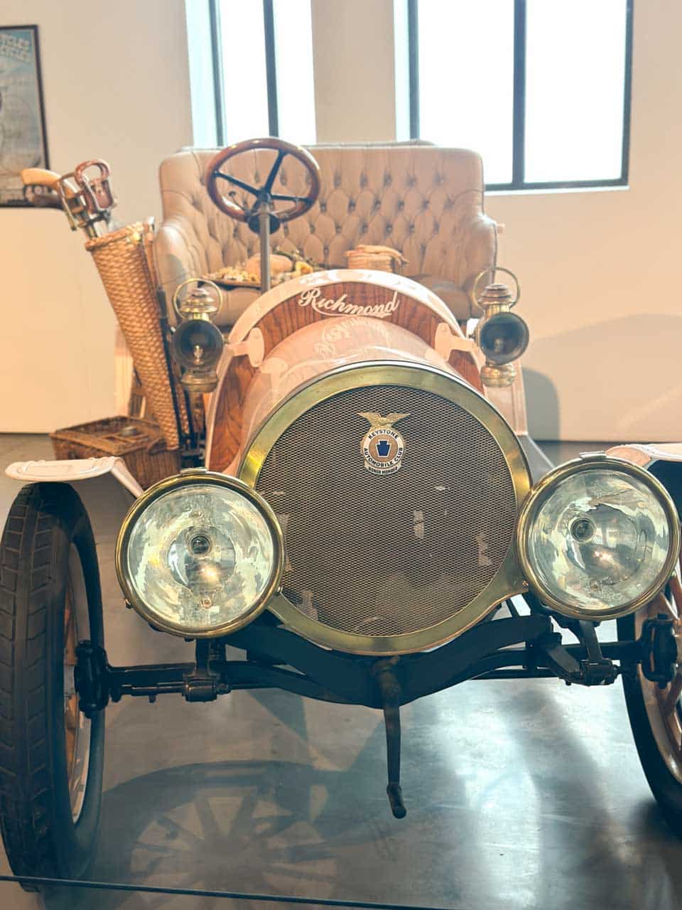 A vintage Richmond car with large round headlights and a picnic basket, displayed at the Automobile and Fashion Museum in Malaga, Spain