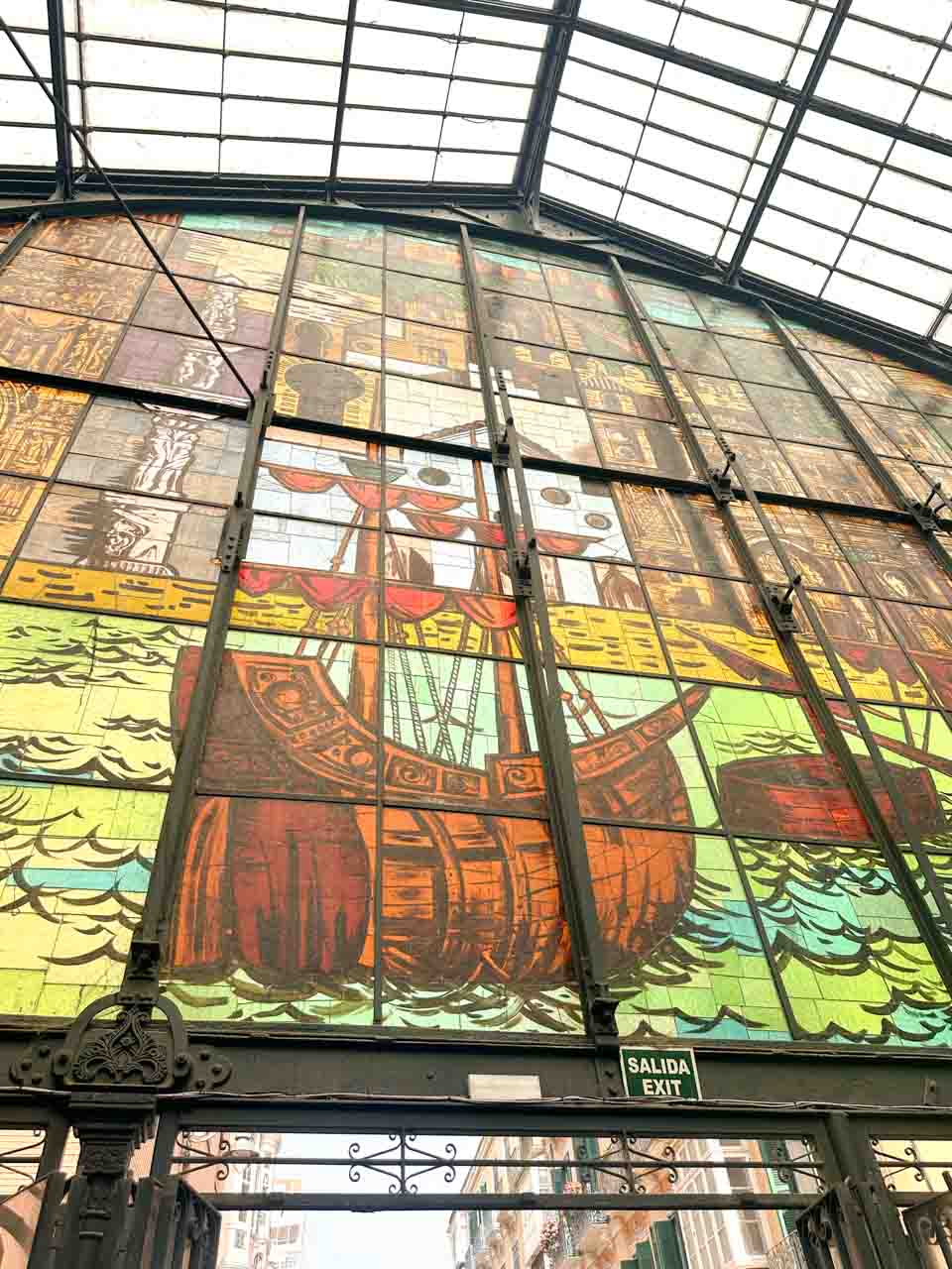 A large stained-glass window depicting historical figures in a boat at the Atarazanas Market in Malaga, Spain