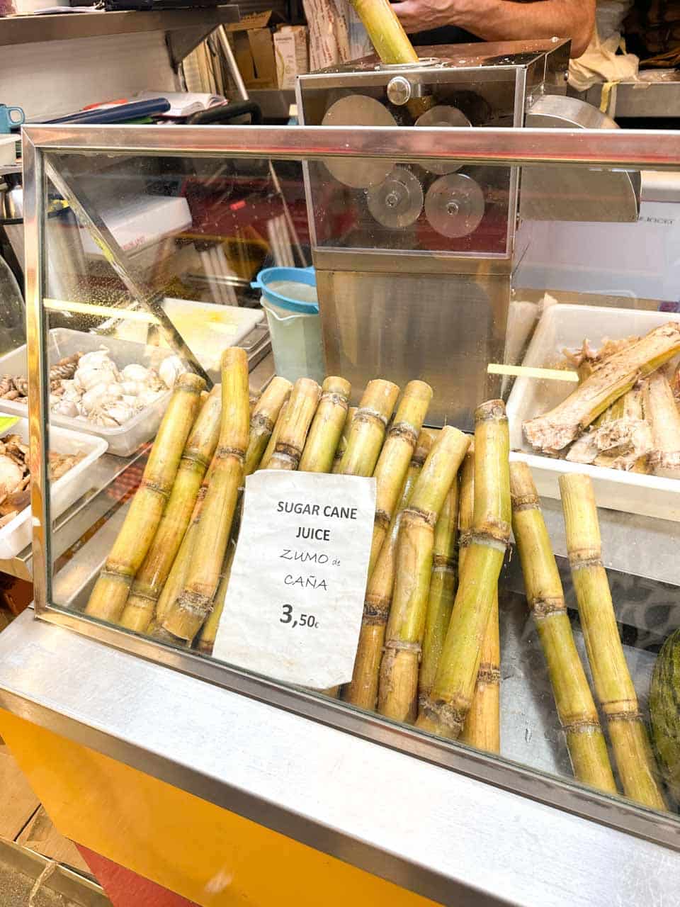 Stalks of sugar cane ready for juicing behind a glass display at the Atarazanas Market in Malaga, Spain