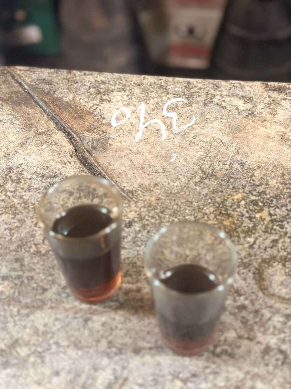 Two small glasses of sherry wine on a bar counter with the price written in chalk at Antigua Casa de Guardia in Malaga, Spain