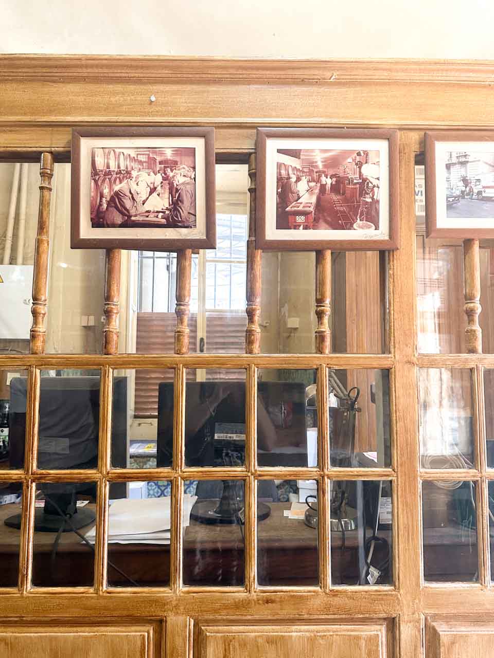 Framed sepia-toned photographs mounted on a wooden partition with glass panes at Antigua Casa de Guardia in Malaga, Spain