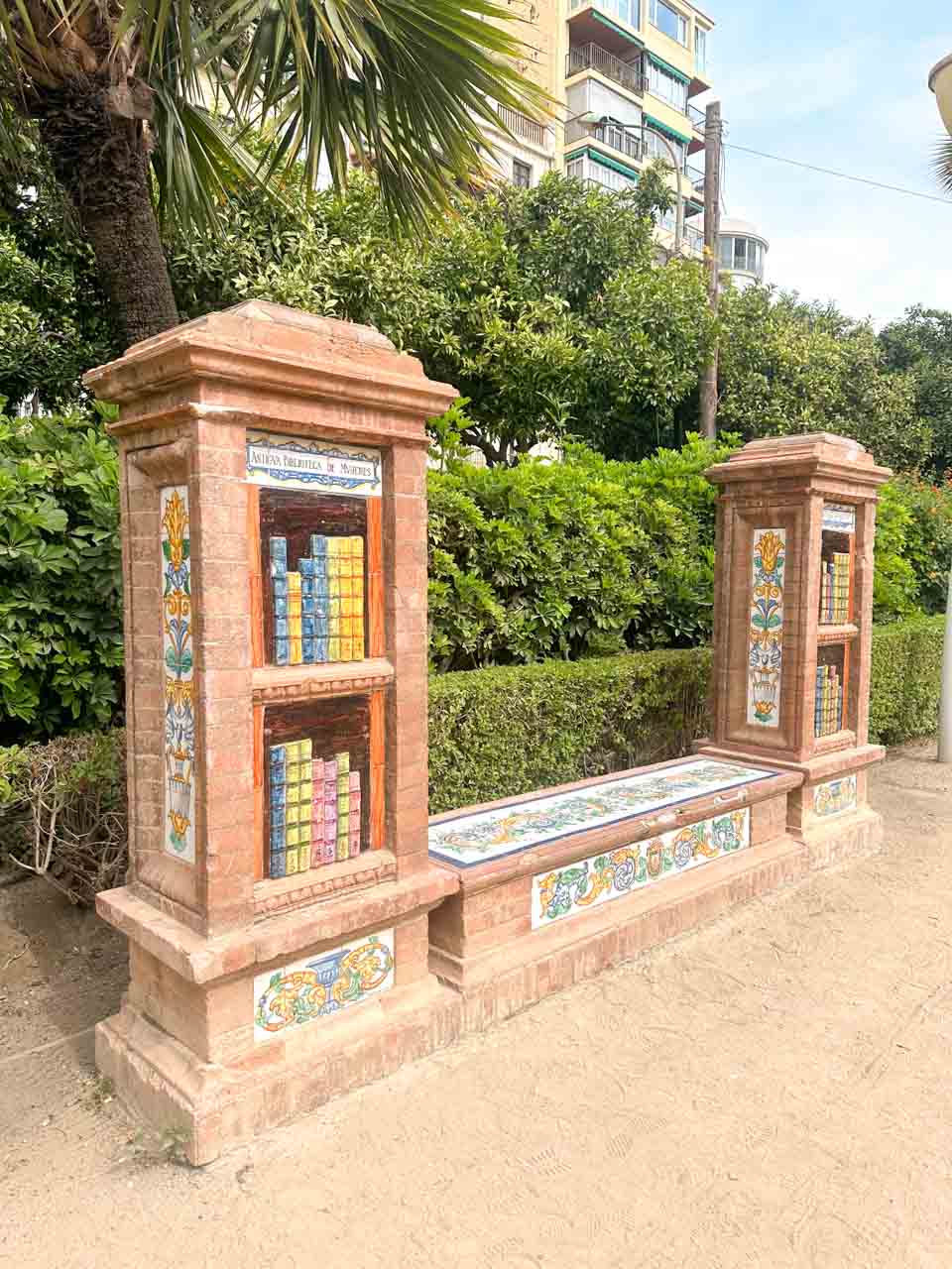 A traditional ceramic-tiled bench with ornate designs, surrounded by lush greenery