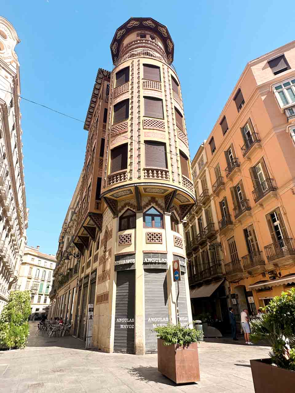 A corner view of a decorative building with balconies and a turret, under a blue sky