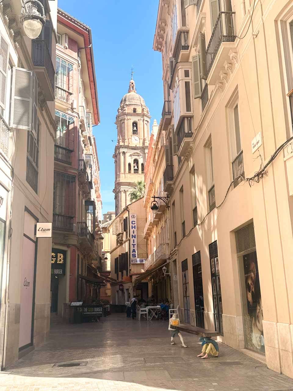 A narrow street in Malaga leading to the Malaga Cathedral, lined with traditional buildings