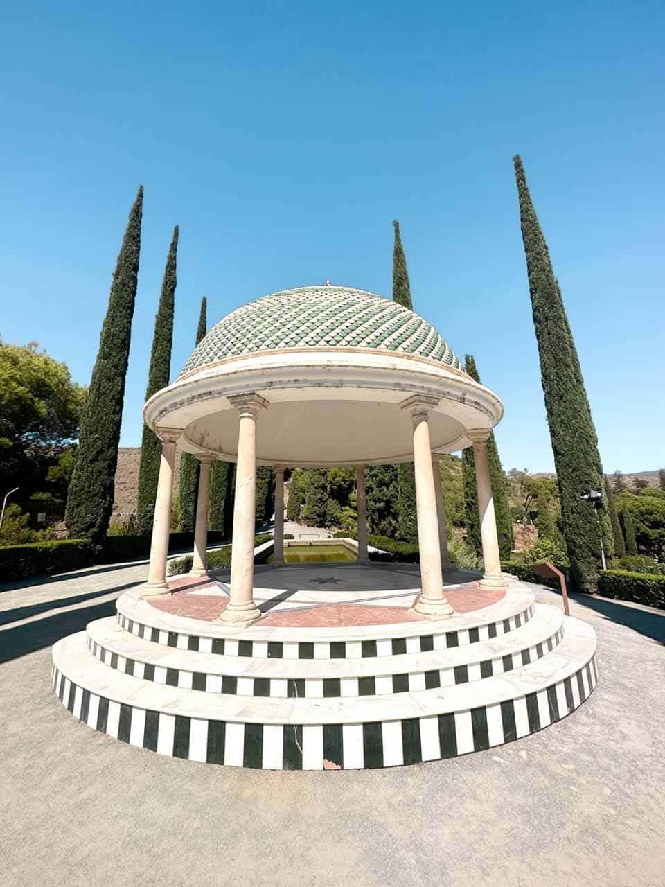 A classical style pavilion with columns and a tiled dome, surrounded by manicured hedges at La Concepci&oacute;n Historical Botanical Garden