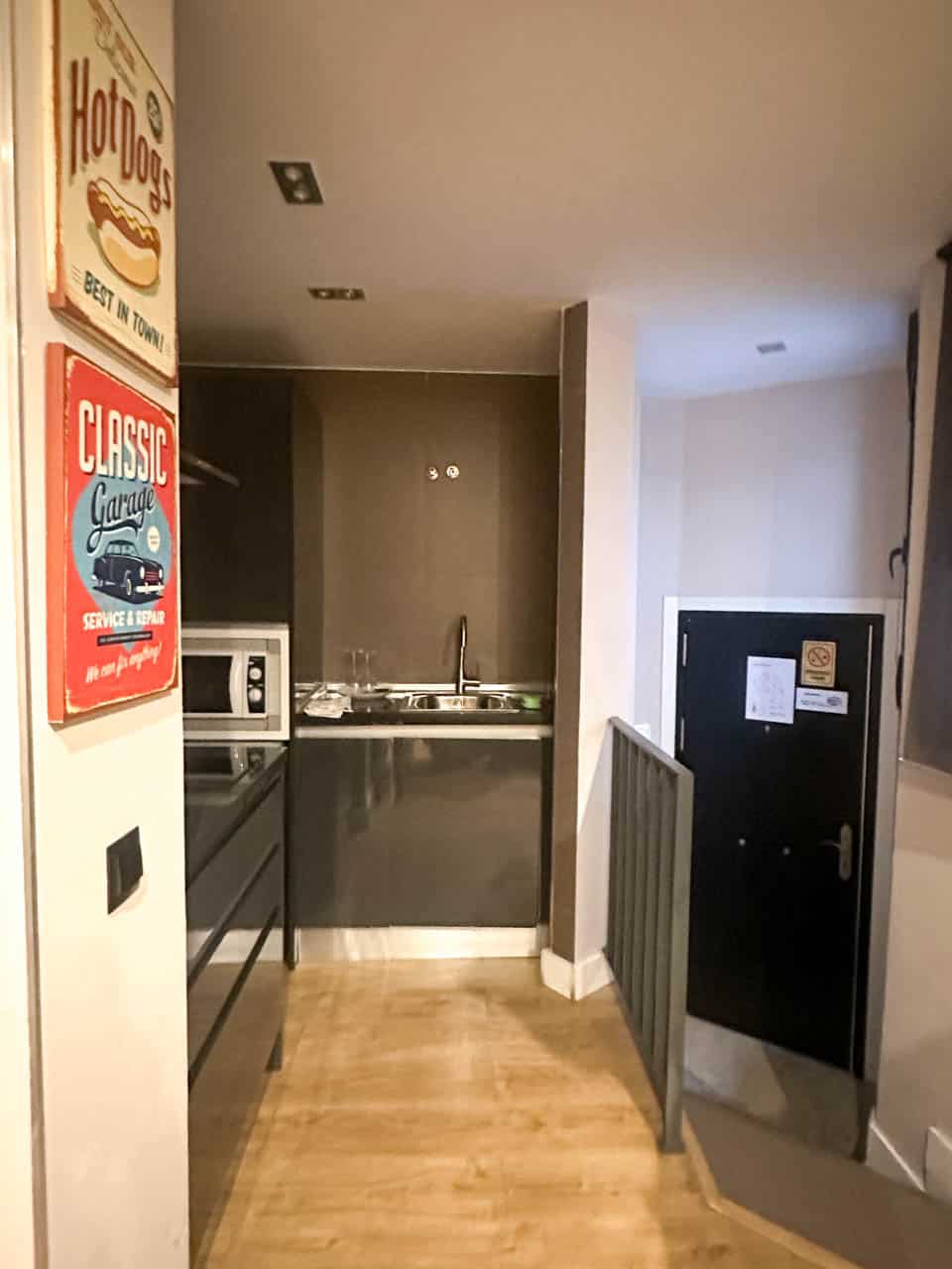 An open-plan kitchen area with wooden floors, and vintage style decorative signs on the wall