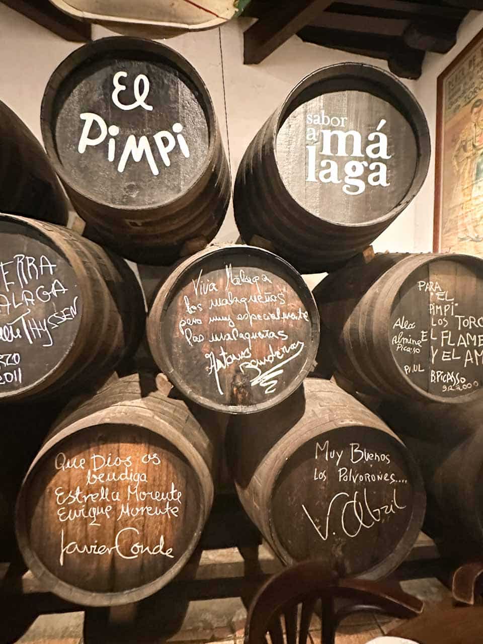 A wall of wooden wine barrels with names and messages written in chalk at Bodega El Pimpi in Malaga, Spain