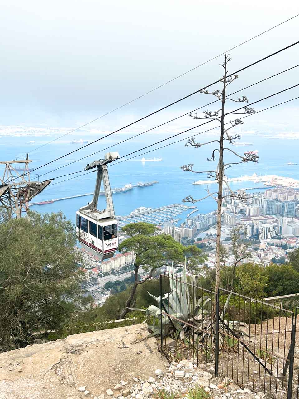 Gibraltar's cable car near the summit, with a backdrop of the cityscape and busy harbour below
