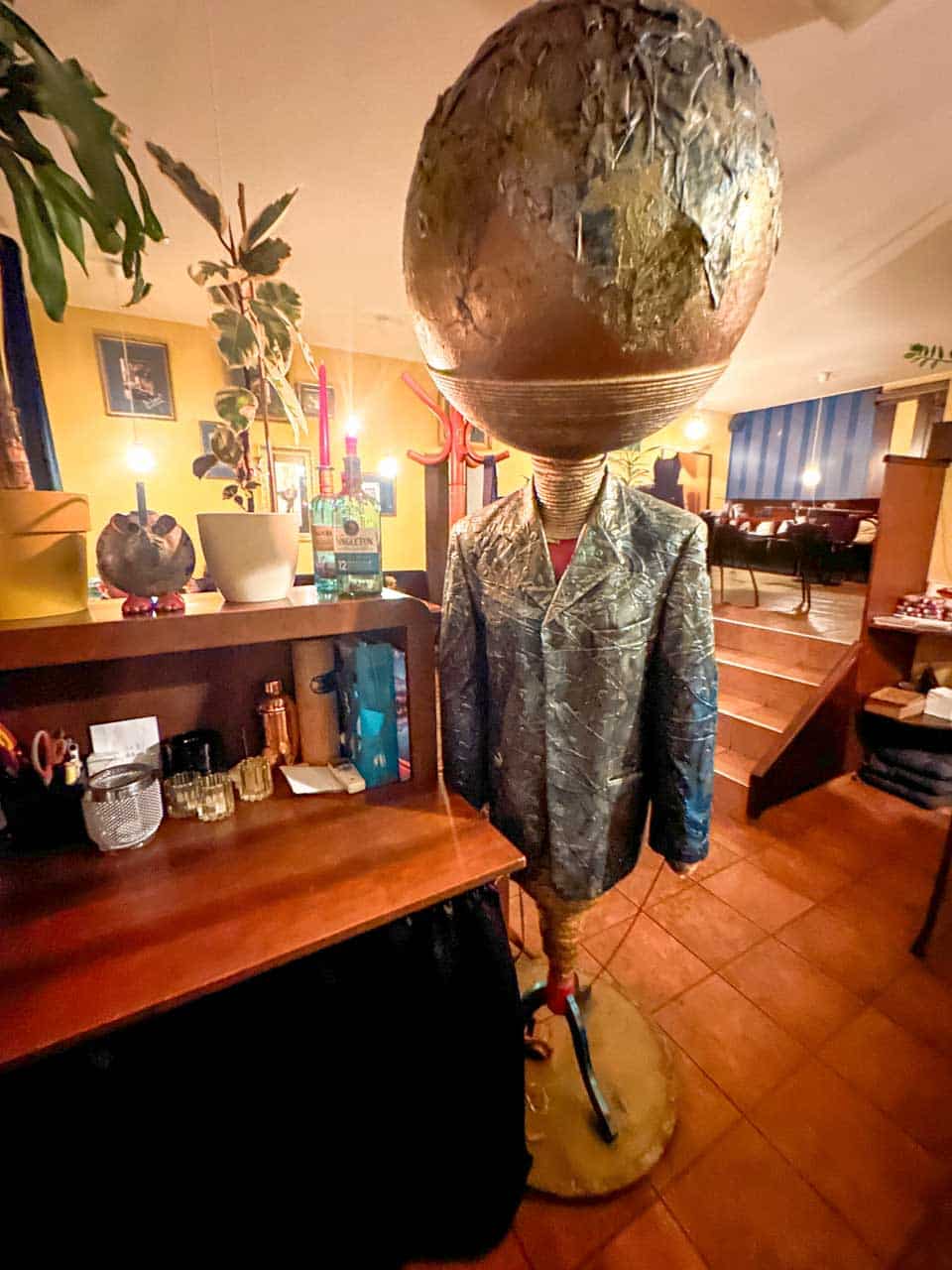 A quirky sculpture with a globe head and a metallic suit displayed inside the Modrá Myš cocktail bar in Ostrava