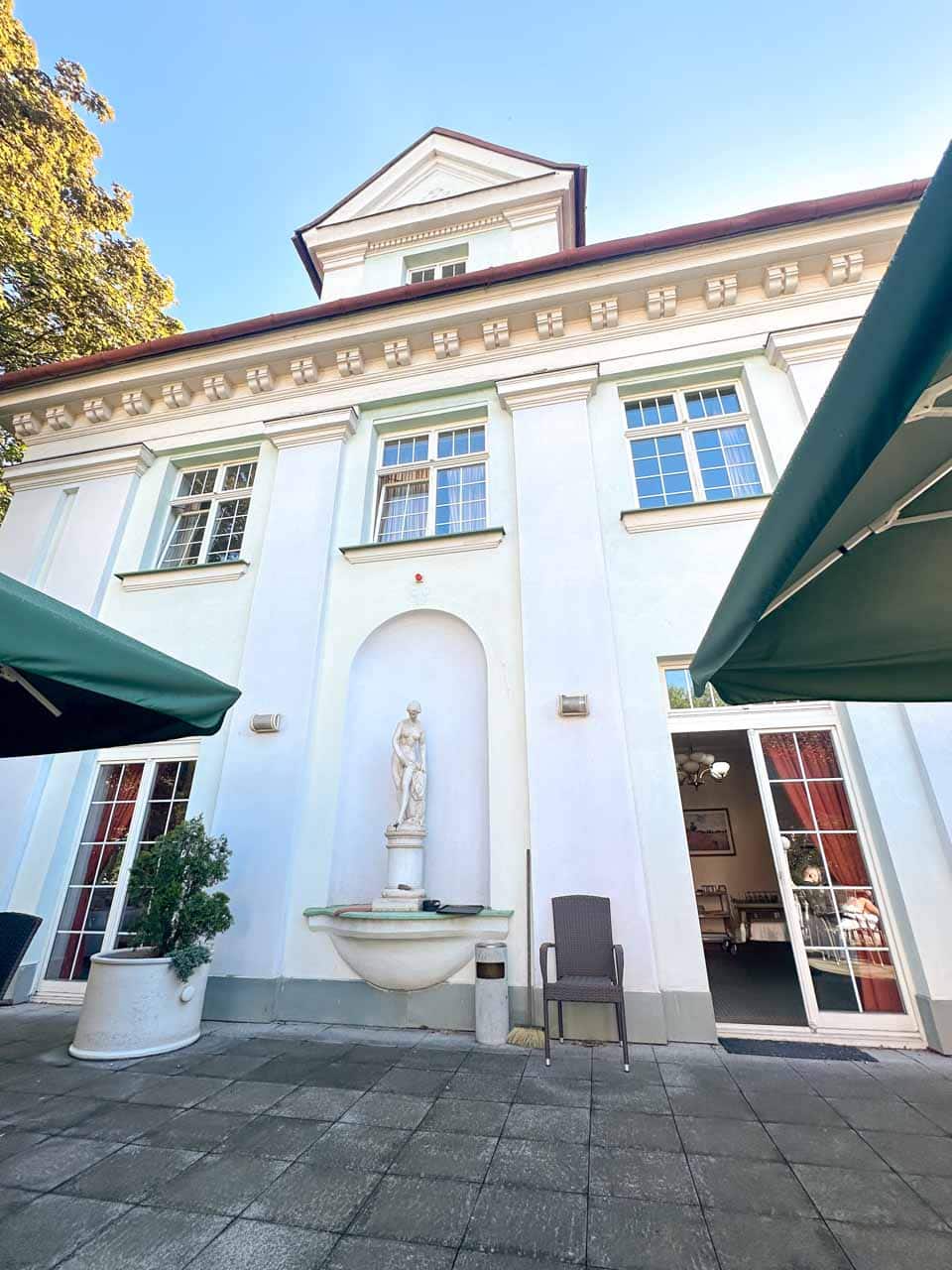 The white facade of Retro Hotel Villa Ostrava with a statue and a fountain on the terrace