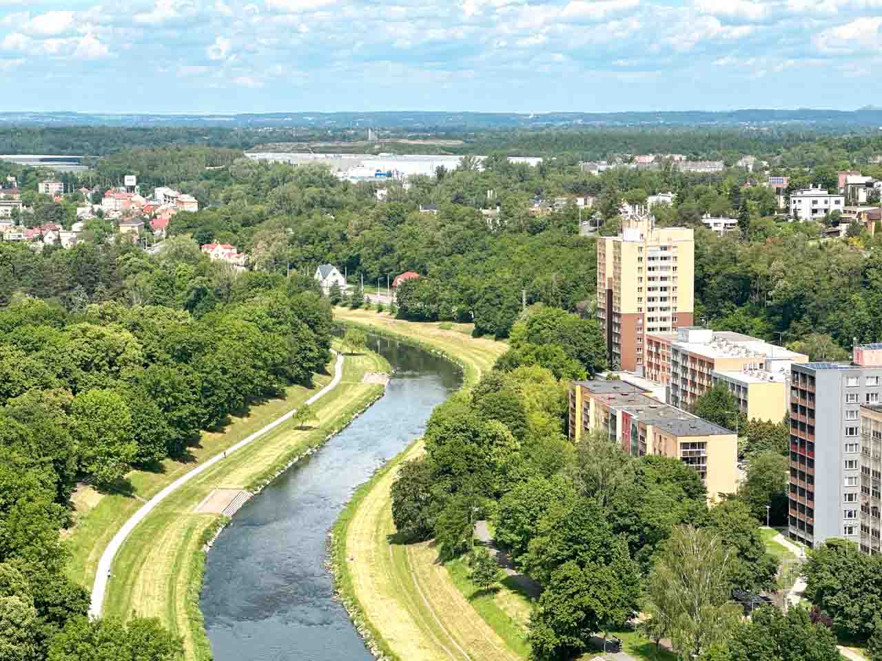 Ostravice river flowing past high-rise buildings and lush green parks seen from the top of the New City Hall Observation Tower in Ostrava