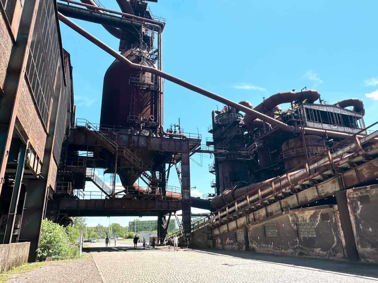Massive industrial machinery with interconnected pipes under a clear sky inside the Dolní Vítkovice complex