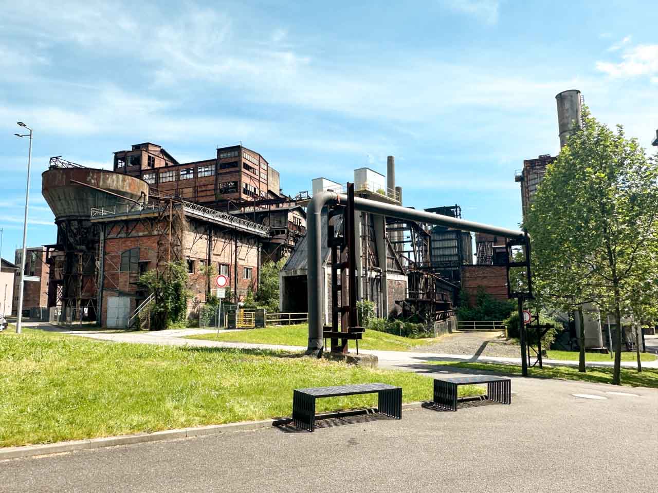 Large, old industrial buildings surrounded by greenery inside the Dolní Vítkovice complex in Ostrava