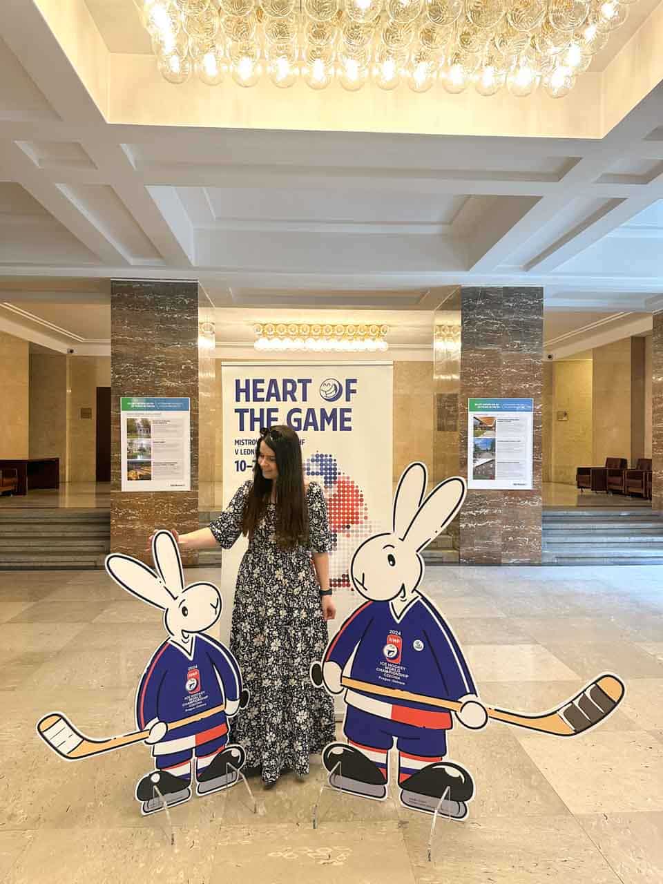 Woman posing with the cutouts of Bob and Bobek, the mascots of the 2024 Ice Hockey World Championships, in the lobby of the New City Hall in Ostrava