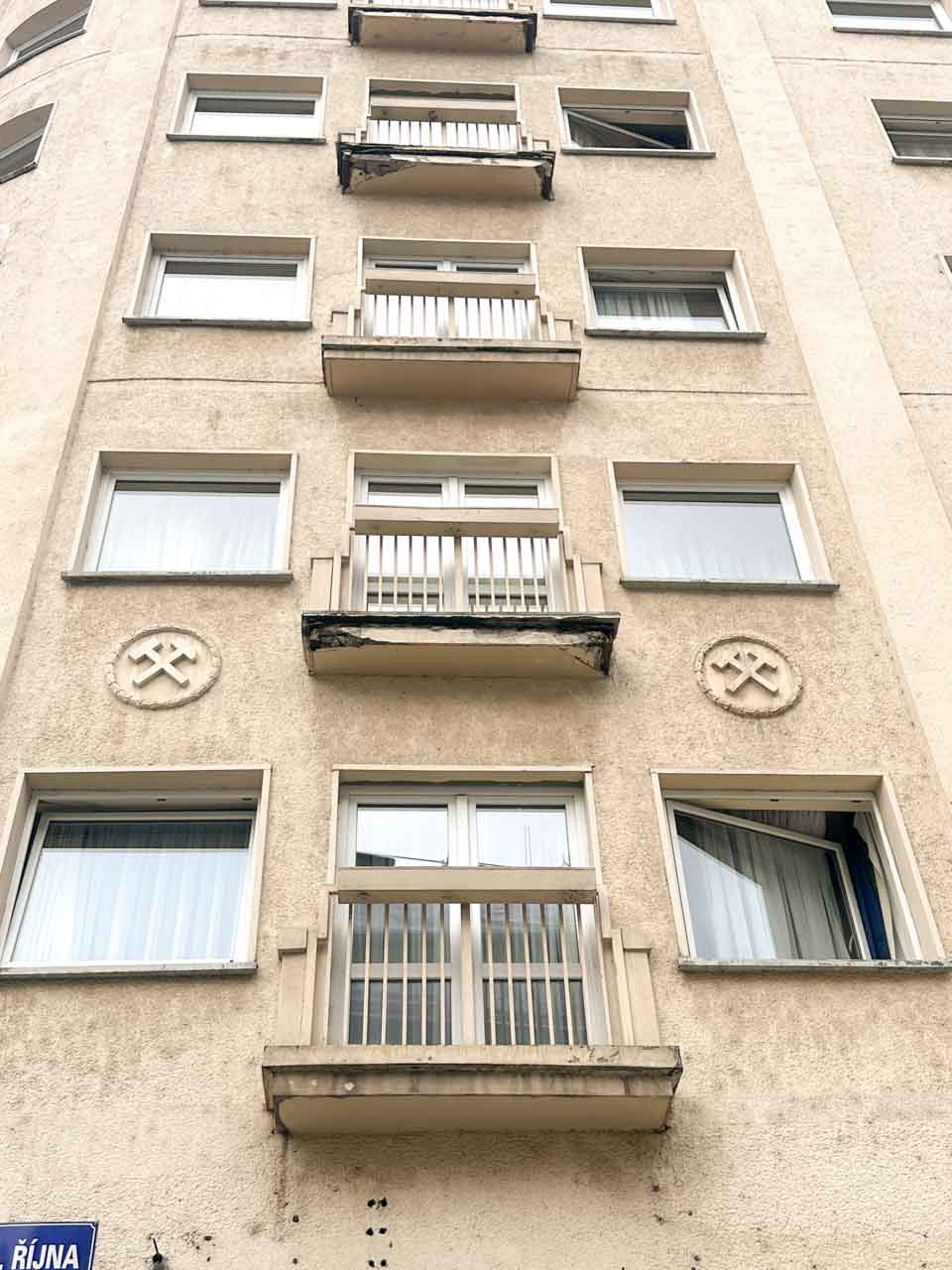 Block of flats with crossed hammers emblem and balconies, symbolising mining in Ostrava