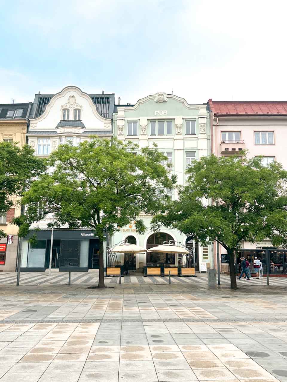 Masaryk Square in Ostrava, lined with trees and surrounded by historic buildings in pastel colours
