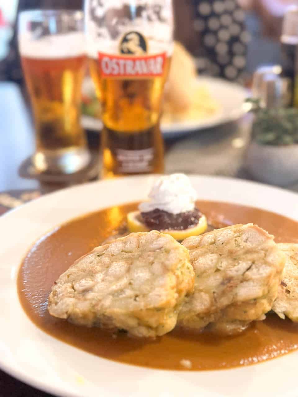 Plate of beef tenderloin with sauce (svíčková) and dumplings and a glass of beer served in the Dáma Pyková Restaurant in Ostrava