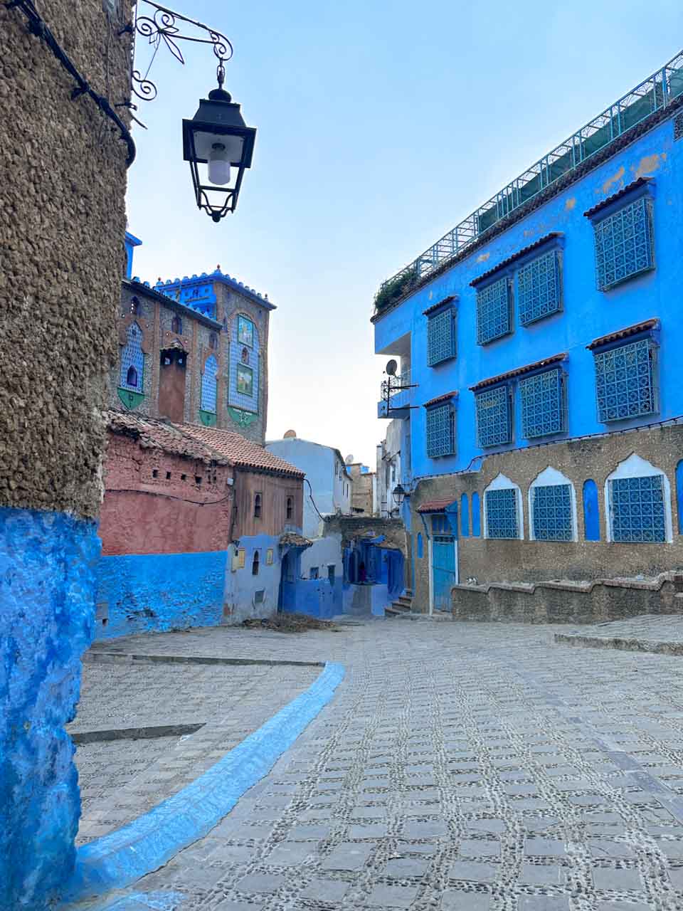 An empty square framed by blue and tan buildings in Chefchaouen, Morocco