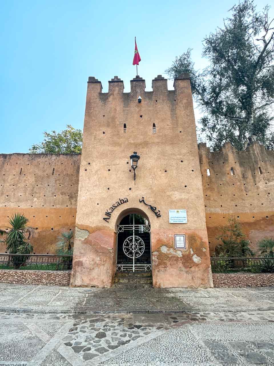A tan-coloured fortress with a Moroccan flag atop, featuring a gated entrance labelled "Alkasaba."