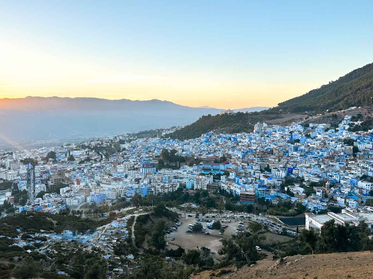 A scenic panoramic view of Chefchaouen at sunset, showcasing the town’s famous blue buildings
