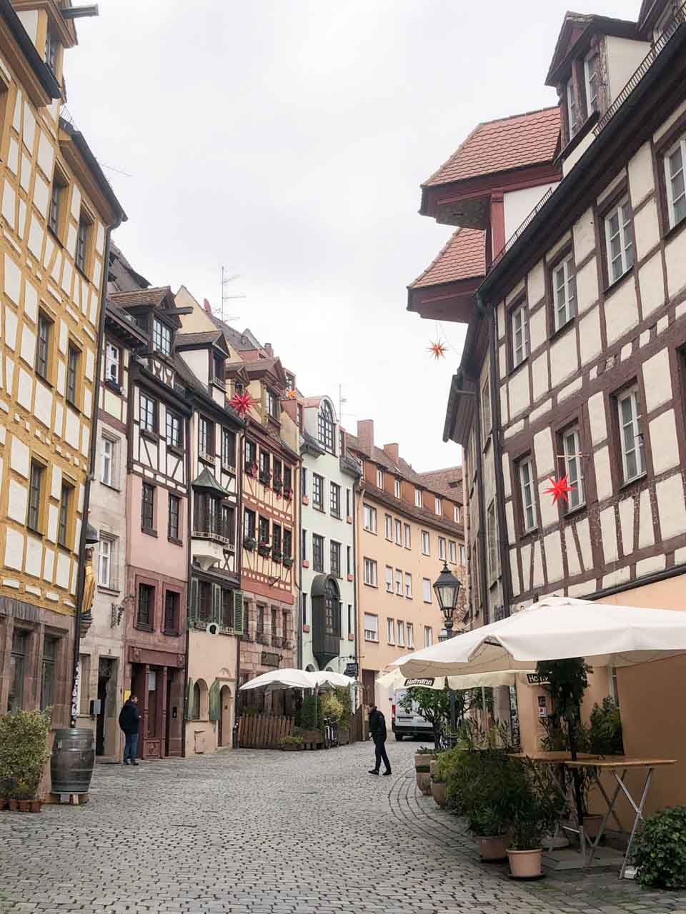 A cobblestone street lined with colourful half-timbered houses and cosy cafés in Nuremberg’s historic old town