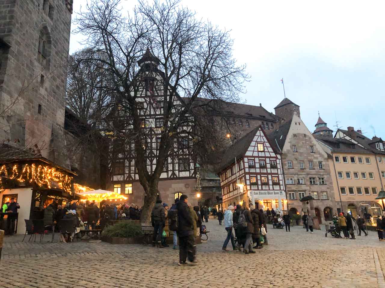The Tiergärtnertor Square in Nuremberg, Germany with half-timbered buildings, festive lights, and people enjoying the lively atmosphere