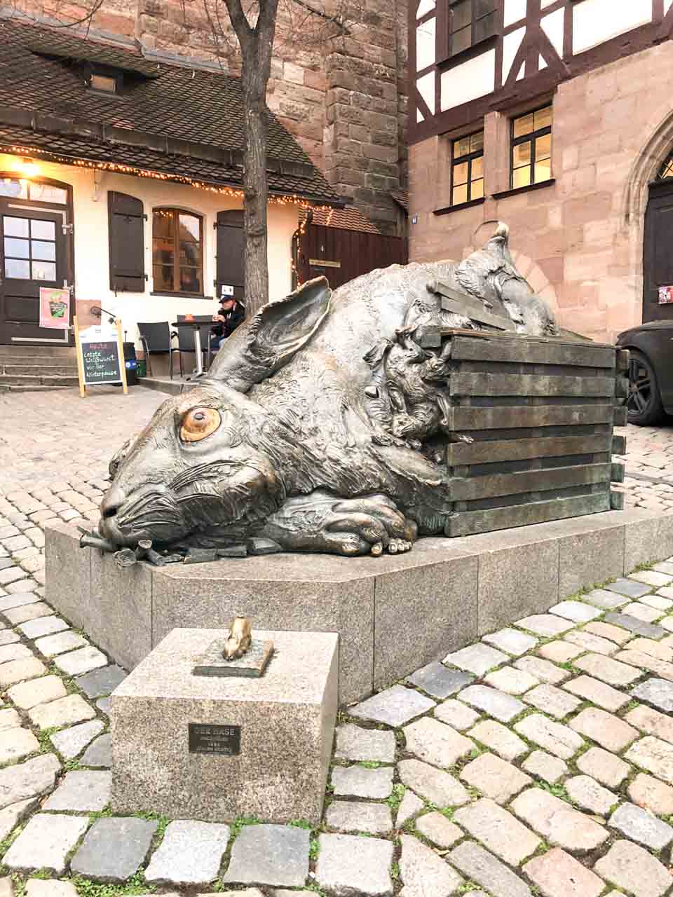 A large bronze rabbit sculpture lying on its side in a cobbled square in Nuremberg, Germany