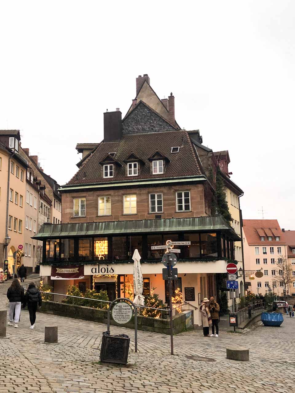 A charming traditional building with a steep roof, a café below, and cobblestone streets in the heart of Nuremberg, Germany