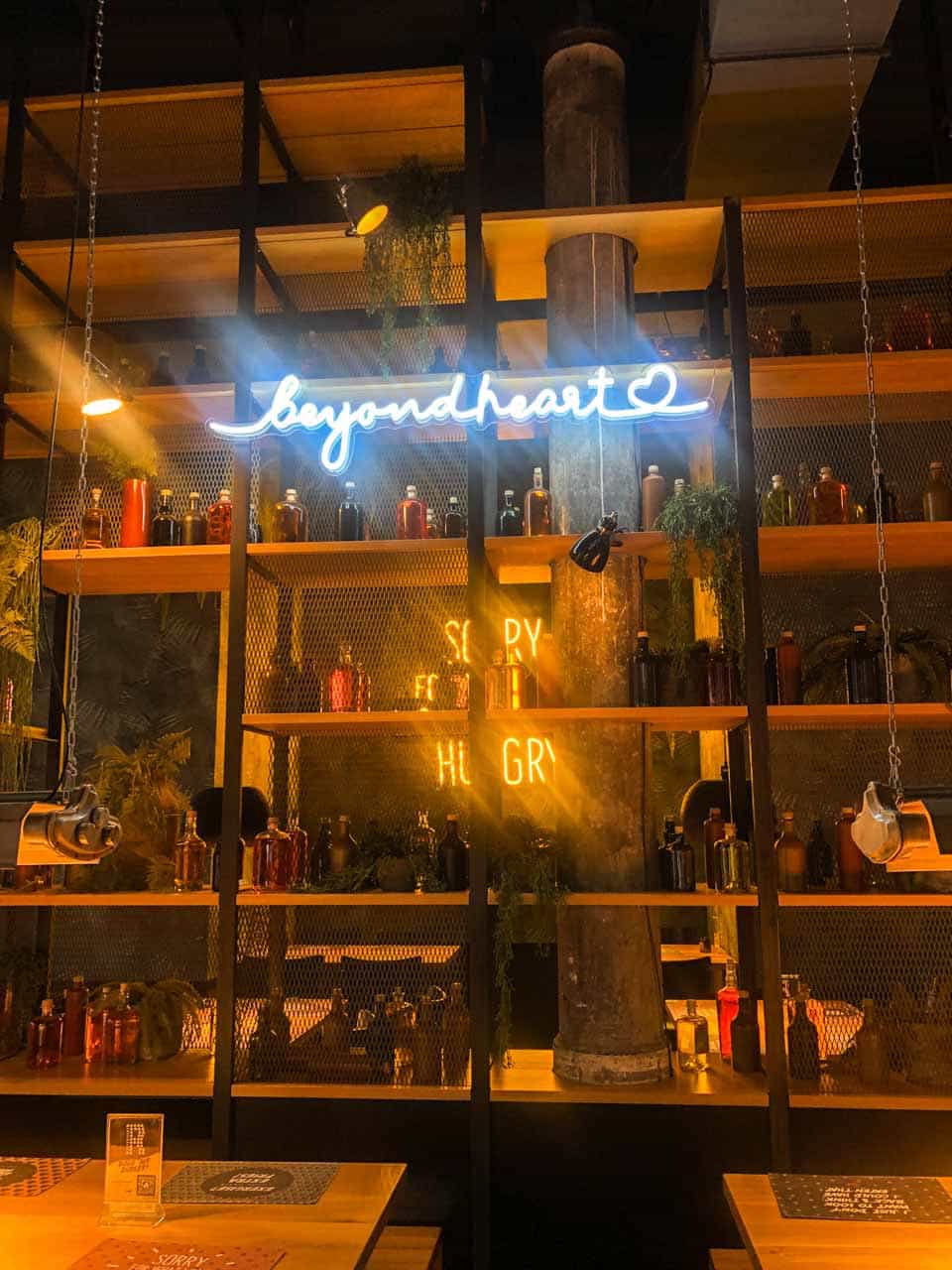 The interior of Burgerheart in Nuremberg with shelves of bottles, greenery, and neon signs