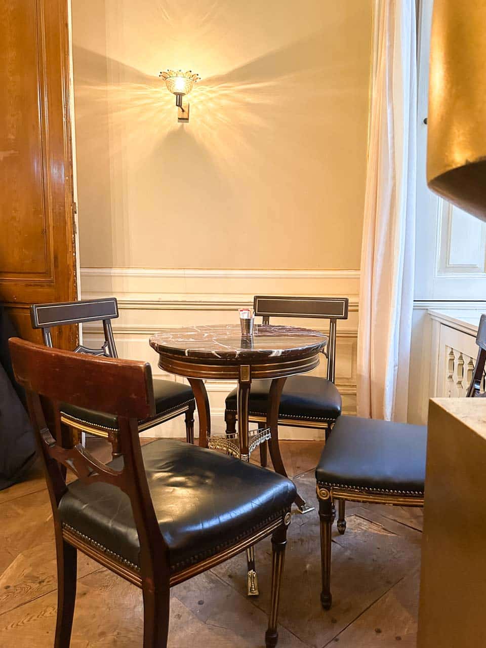 A cosy corner inside Café Demel in Vienna, with an elegant marble-top table surrounded by black leather chairs and warm lighting