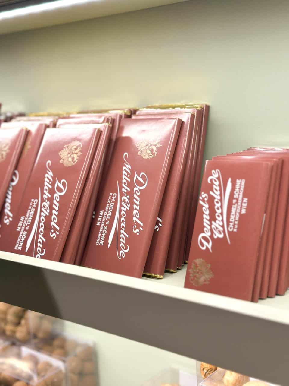 Rows of elegant Demel's chocolate bars in brown wrappers displayed on a shelf