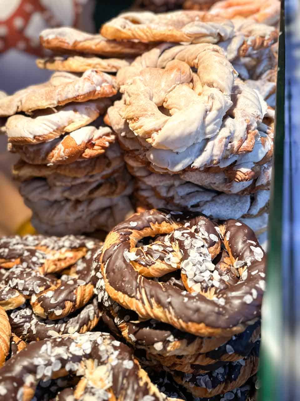 Stacks of freshly baked pretzels, some drizzled with chocolate and sprinkled with almonds, displayed at a Christmas market stall in Vienna