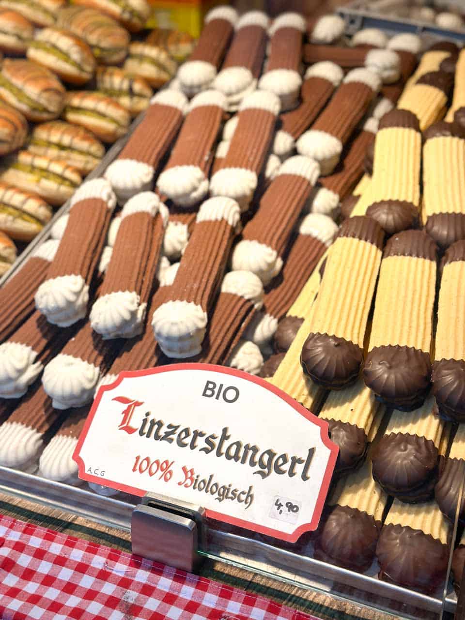 Rows of Linzer biscuits with chocolate and cream detailing on display, labelled as organic with a red-and-white sign