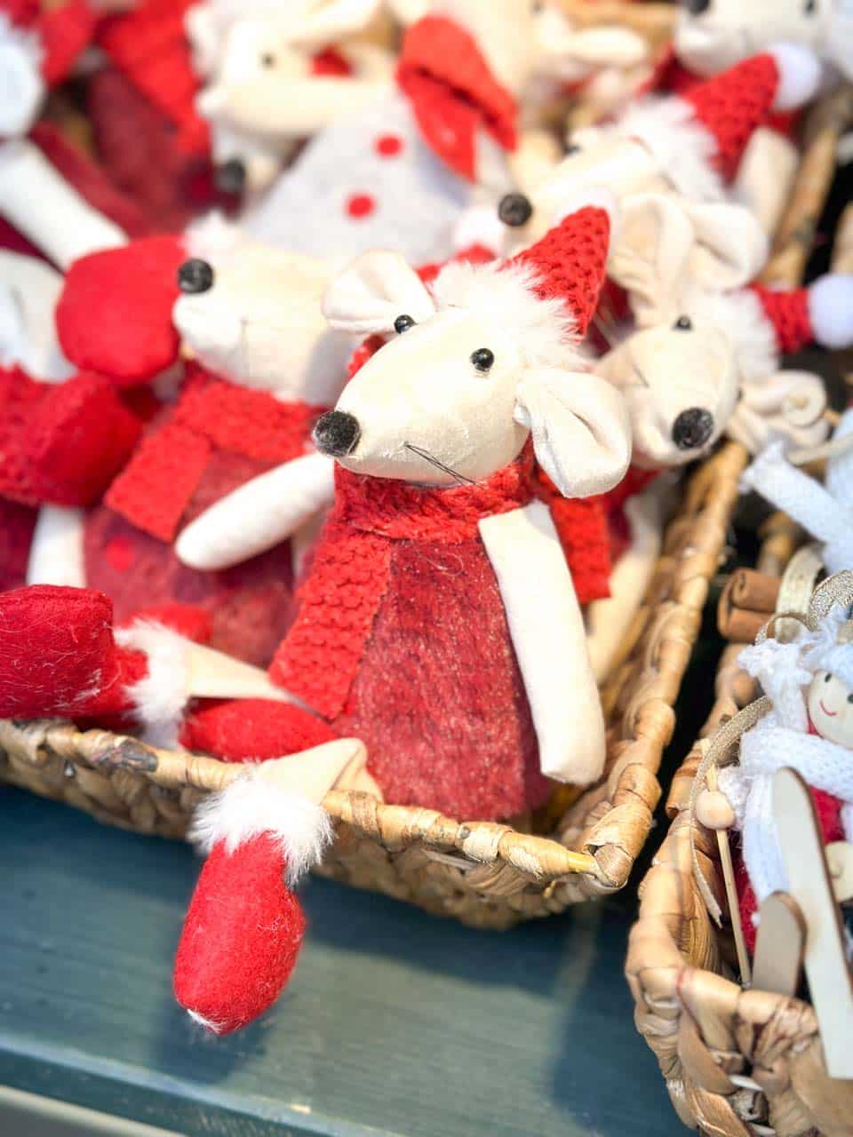 Soft plush mice ornaments dressed in red outfits and Santa hats, arranged in woven baskets at one of the Vienna Christmas markets