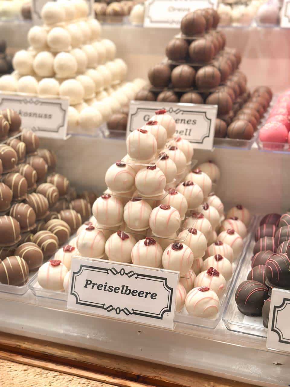 A close-up of cranberry-flavoured marzipan balls with delicate red berry toppings, arranged in a pyramid