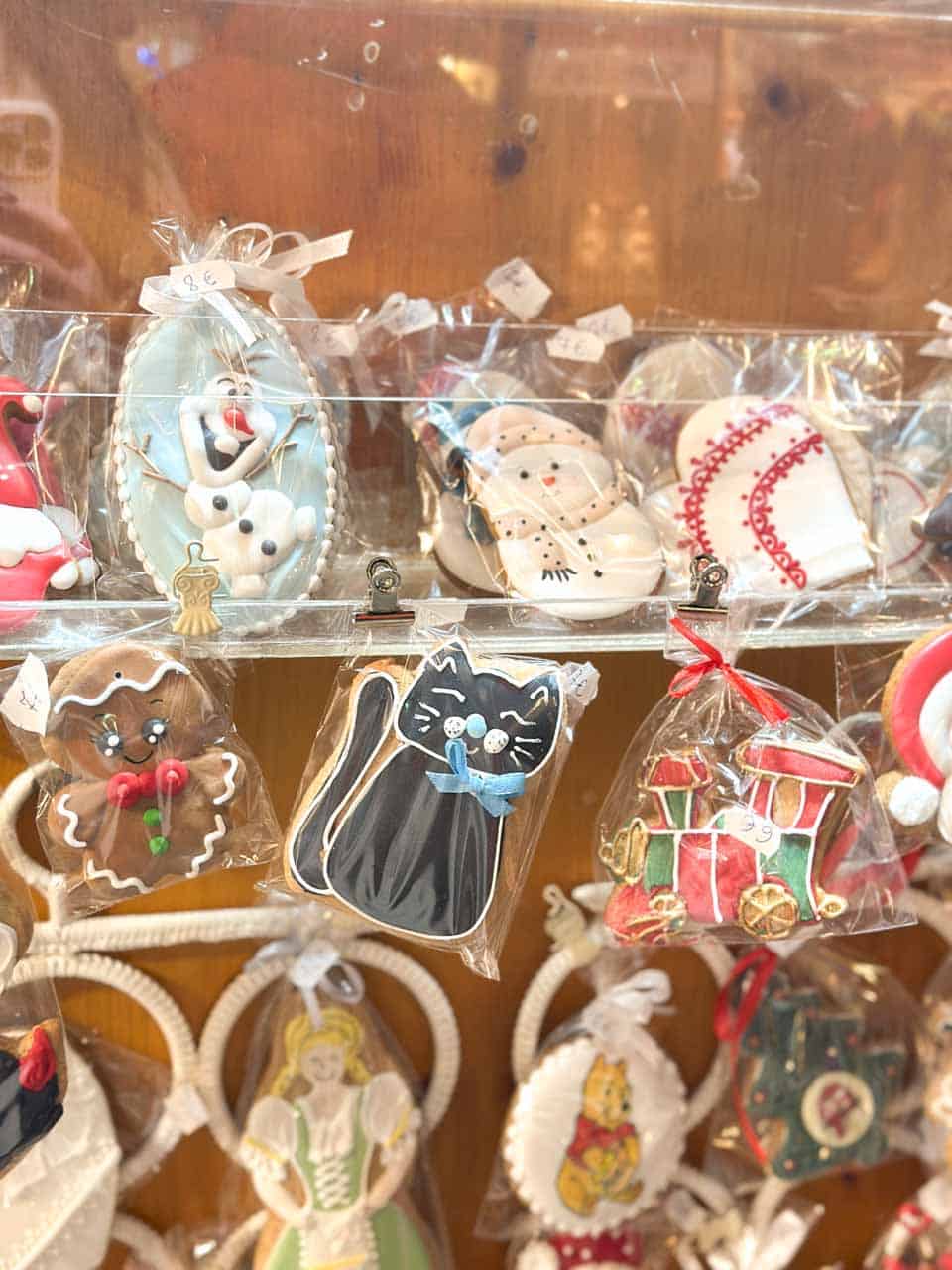 Colourful gingerbread cookies shaped like a cat, snowmen, and festive trains, wrapped in clear bags at a Christmas market in Vienna