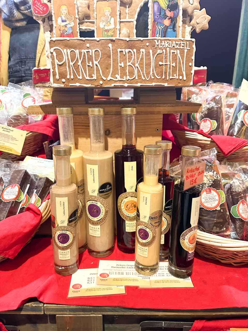 Bottles of Austrian liqueurs displayed with a gingerbread sign reading “Pirker Lebkuchen” at a festive Christmas market stall