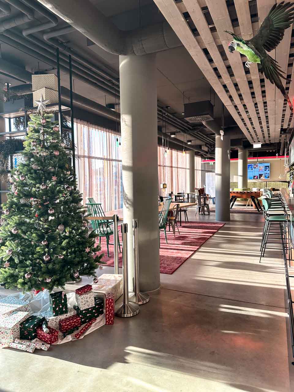 A festive hotel lobby with a decorated Christmas tree and wrapped presents underneath
