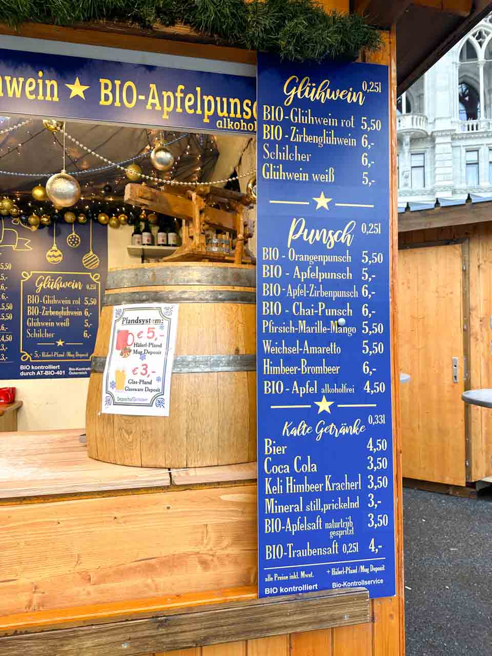 A menu board at a Christmas market stall on Rathausplatz in Vienna listing warm drinks like Glühwein and punch