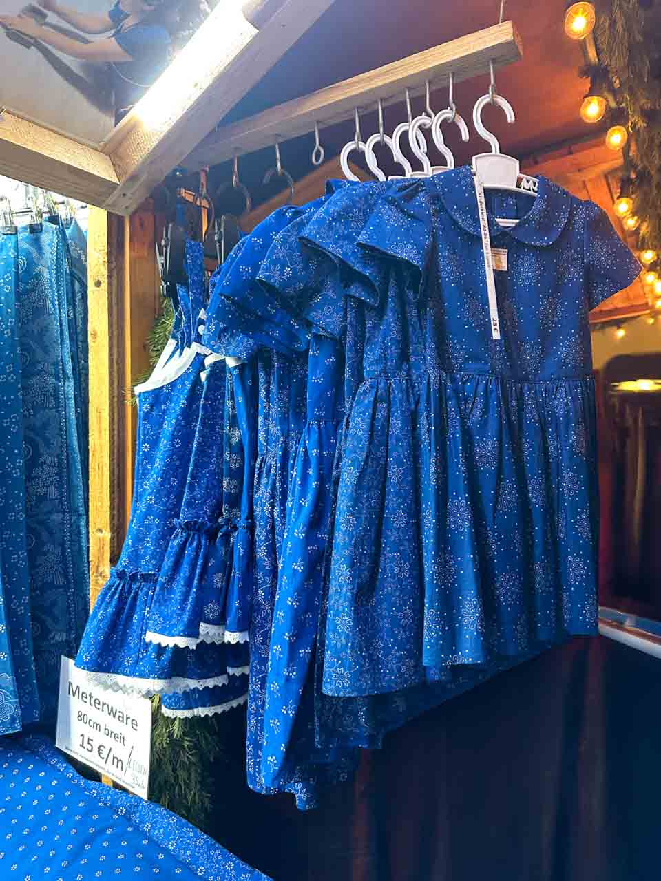 A market stall displaying traditional blue dresses with delicate white patterns