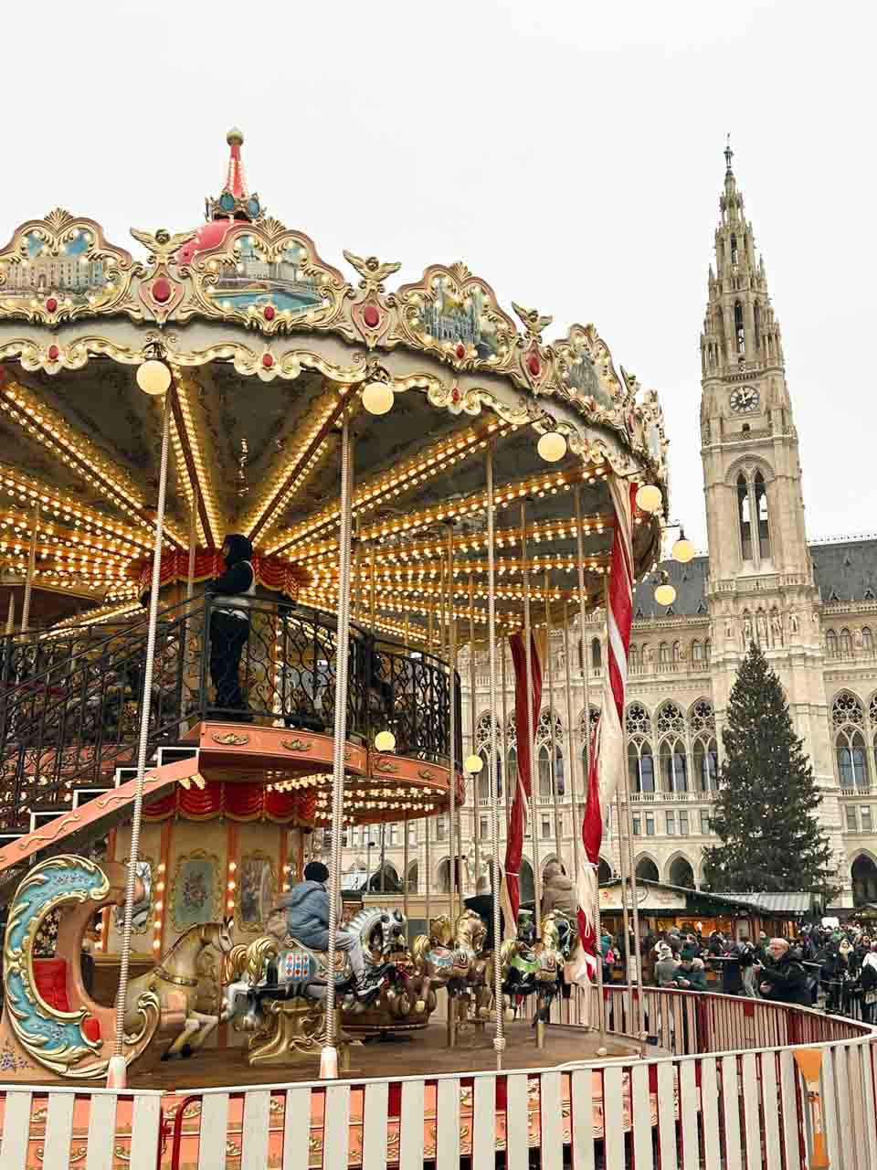 A brightly lit carousel set against Vienna’s Rathaus and a large Christmas tree