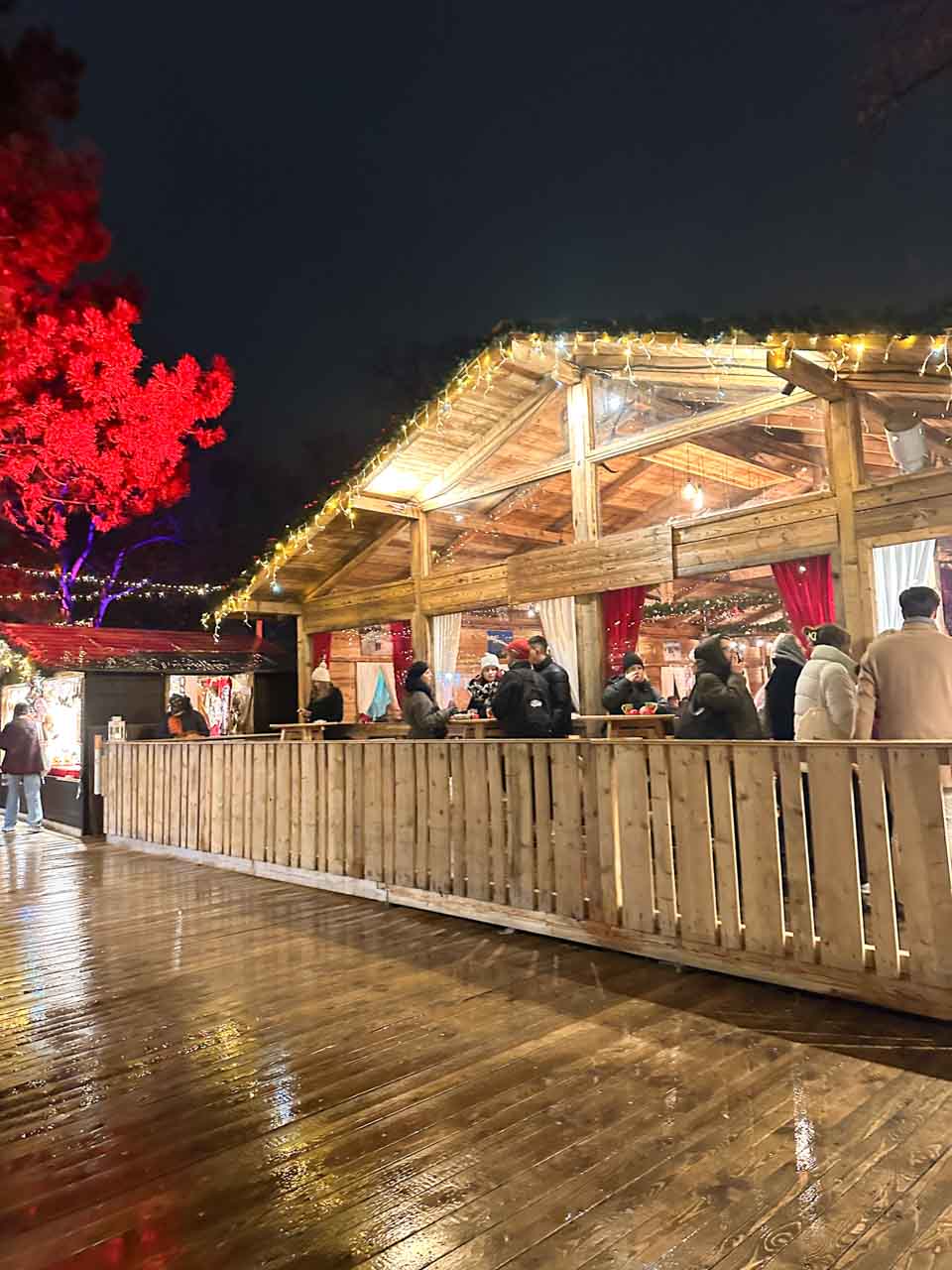 A wooden chalet-style hut decorated with fairy lights at the University of Vienna campus Christmas market