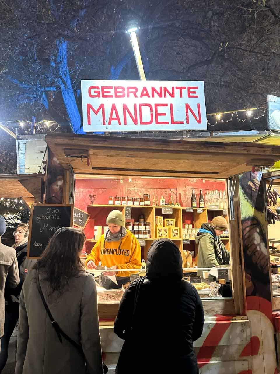 A roasted almonds stall with a bright "Gebrannte Mandeln" sign at the Karlsplatz Christmas market in Vienna, Austria