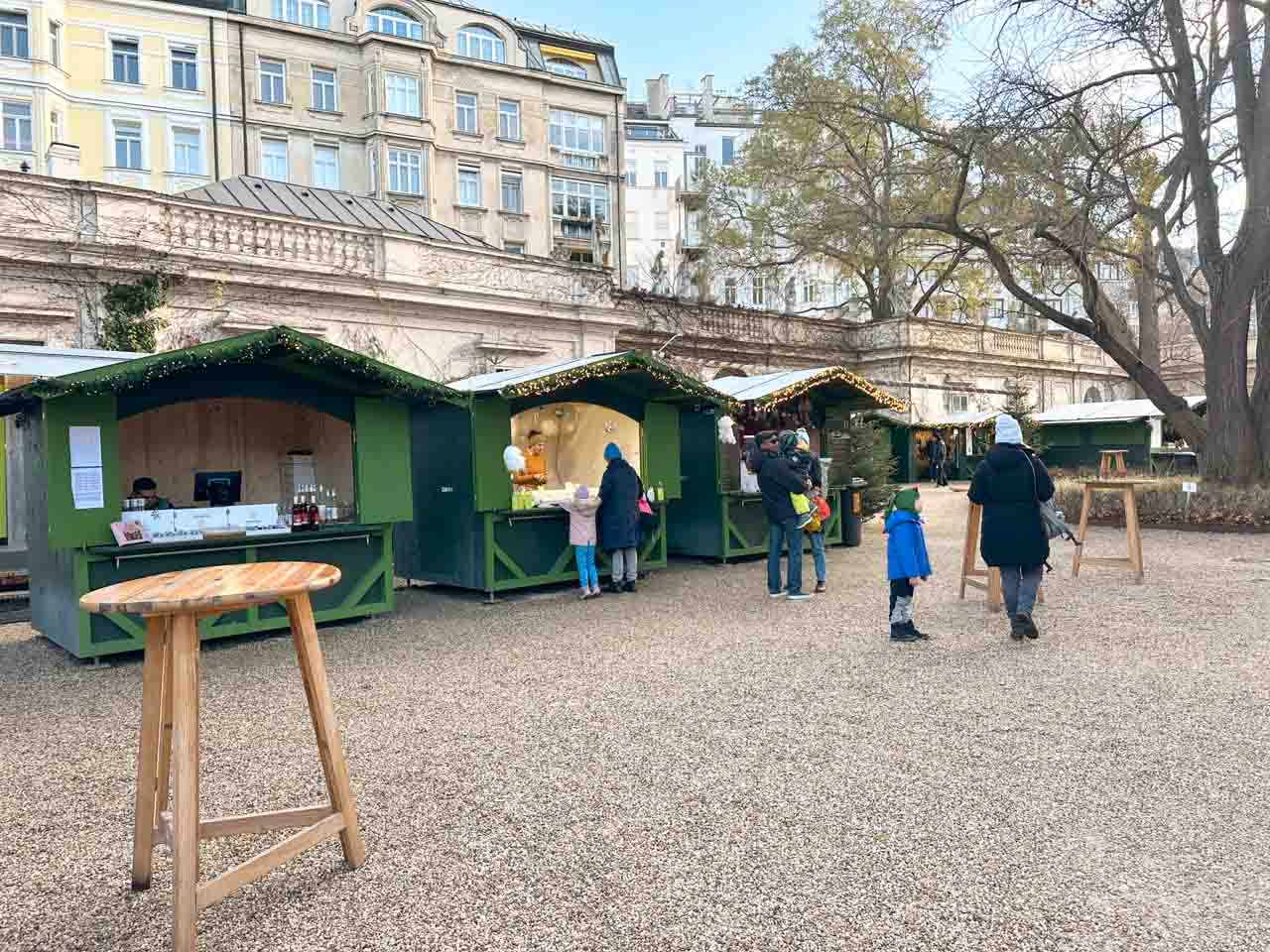 Advent im Gartenpalais Liechtenstein Christmas market in Vienna with green stalls selling crafts and treats under a clear blue sky