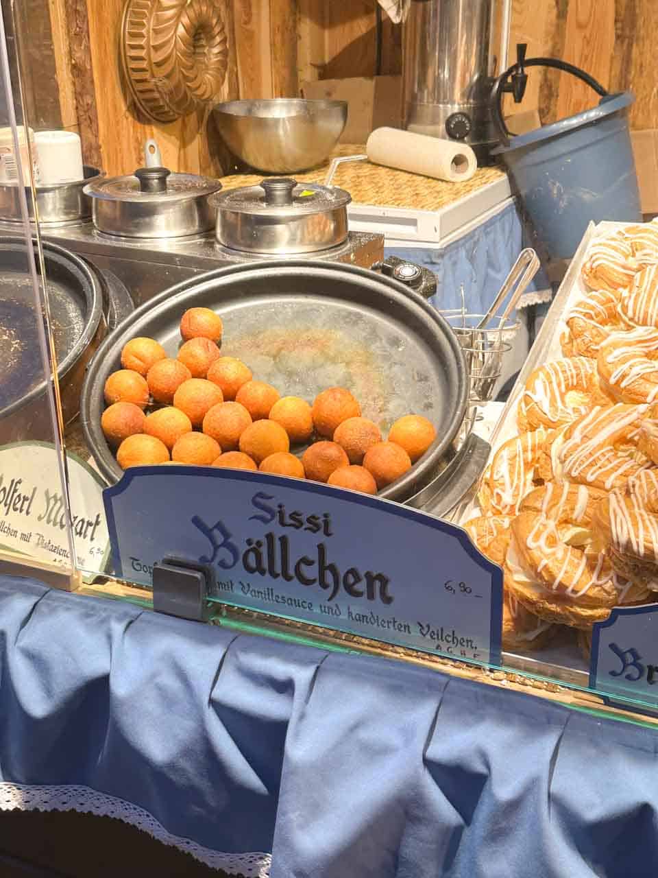 Golden fried Sissi Bällchen doughnuts served at a festive market stall on Maria-Theresien-Platz in Vienna