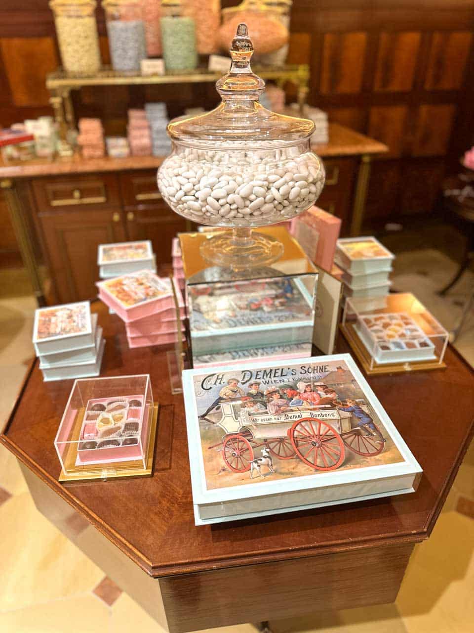 A display inside Café Demel with jars of sugared almonds and vintage-style bonbon boxes, surrounded by pastel-coloured sweets