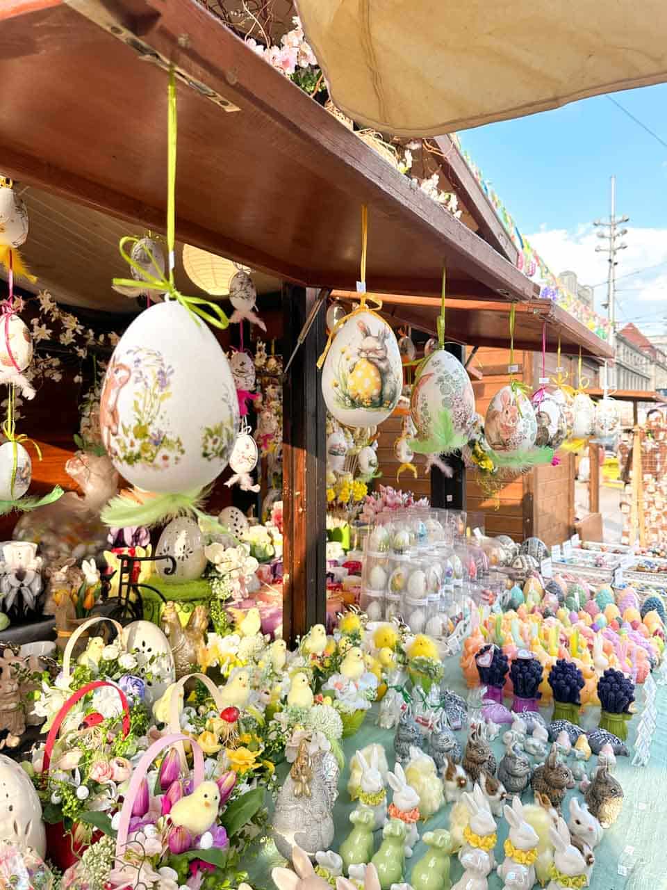 A market stall full of hanging painted Easter eggs, chick decorations, and spring-themed ornaments