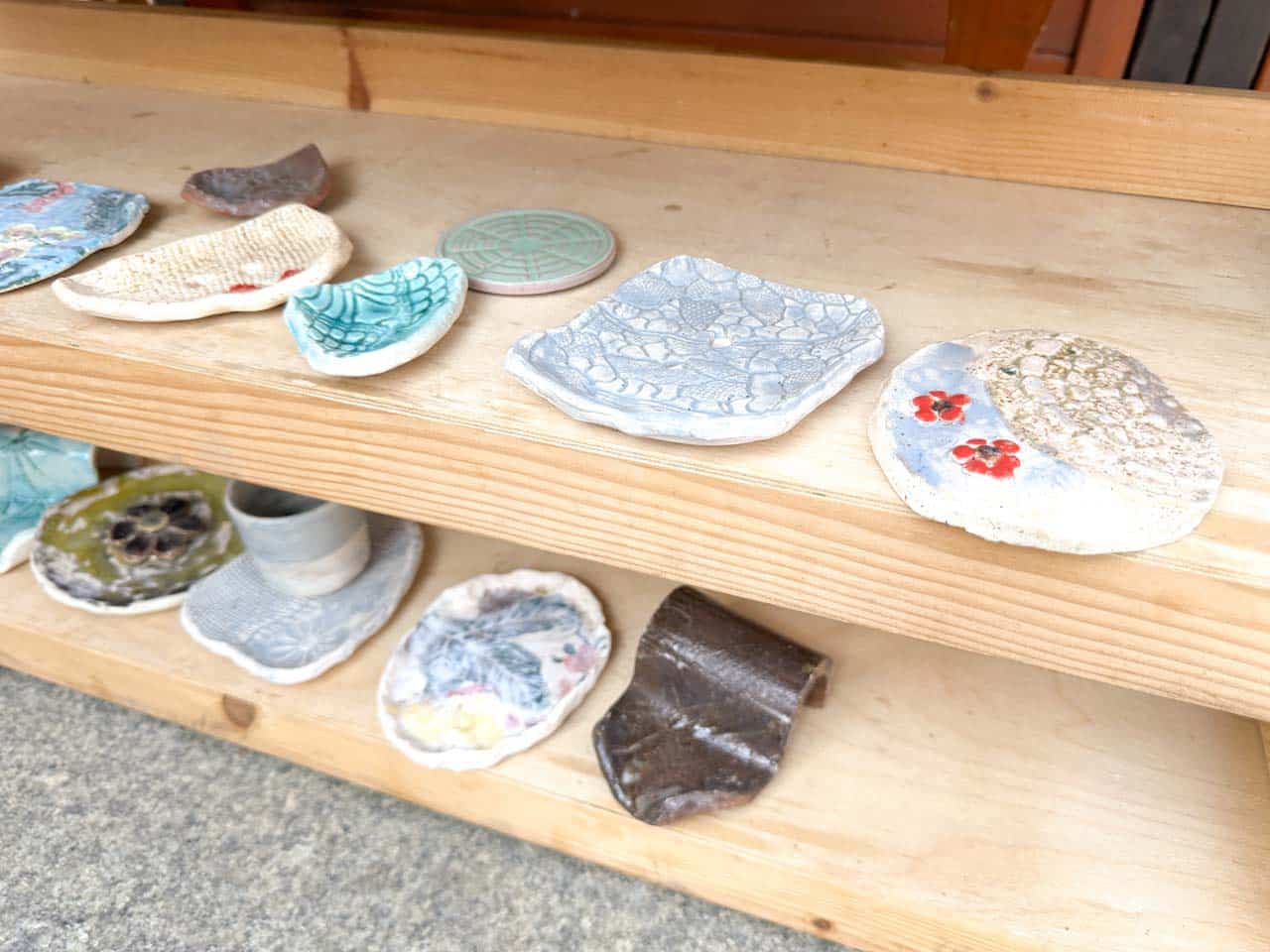 Handmade ceramic soap dishes in soft pastel colours, laid out on wooden shelves at the Katowice Easter Market
