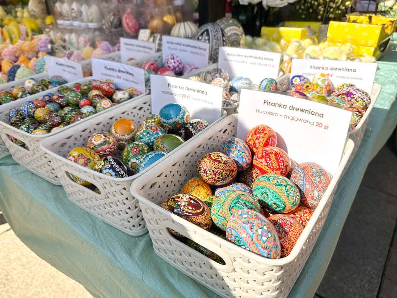 Baskets of hand-painted wooden Easter eggs in bright folk patterns, labelled by style and price