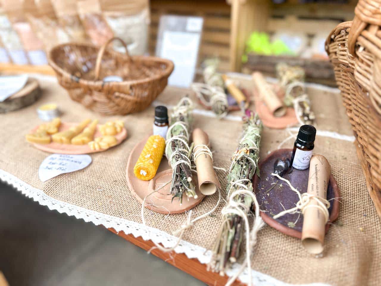 A natural wellness stall with herbal bundles, rolled candles, and essential oils laid out on burlap
